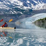 Students sea kayak past glacier
