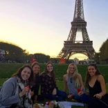 group of students having a picnic on the lawn in front of the Eiffel Tower at sunset